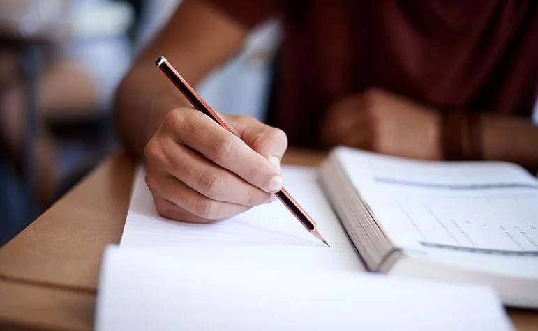Student studying the Indiana CDL manual with pencil and notebook notes for the 2026 BMV knowledge exams